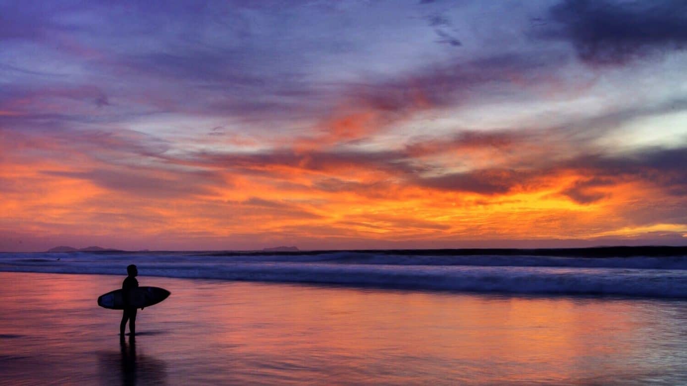 Oranger Sonnenuntergang am Meer mit Surfer